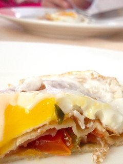 Una foto de Crêpes rellenas con jamón, tomate y cebolla salteado con albahaca y huevo frito