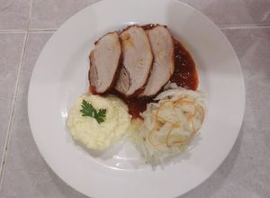 Una foto de Pierna de puerco en achiote acompañado de chucrut y puré de papa