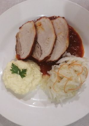 Una foto de Pierna de puerco en achiote acompañado de chucrut y puré de papa