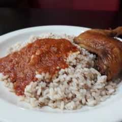 A picture of Ofada rice with tomato stew and chicken.