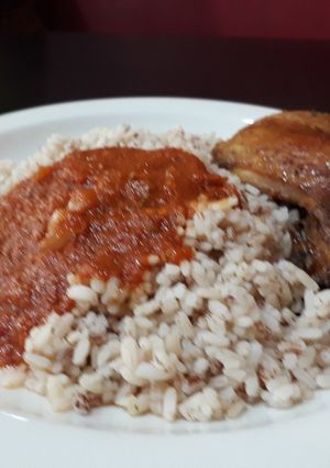 A picture of Ofada rice with tomato stew and chicken.
