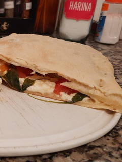Una foto de Calzone de queso, tomate y rúcula