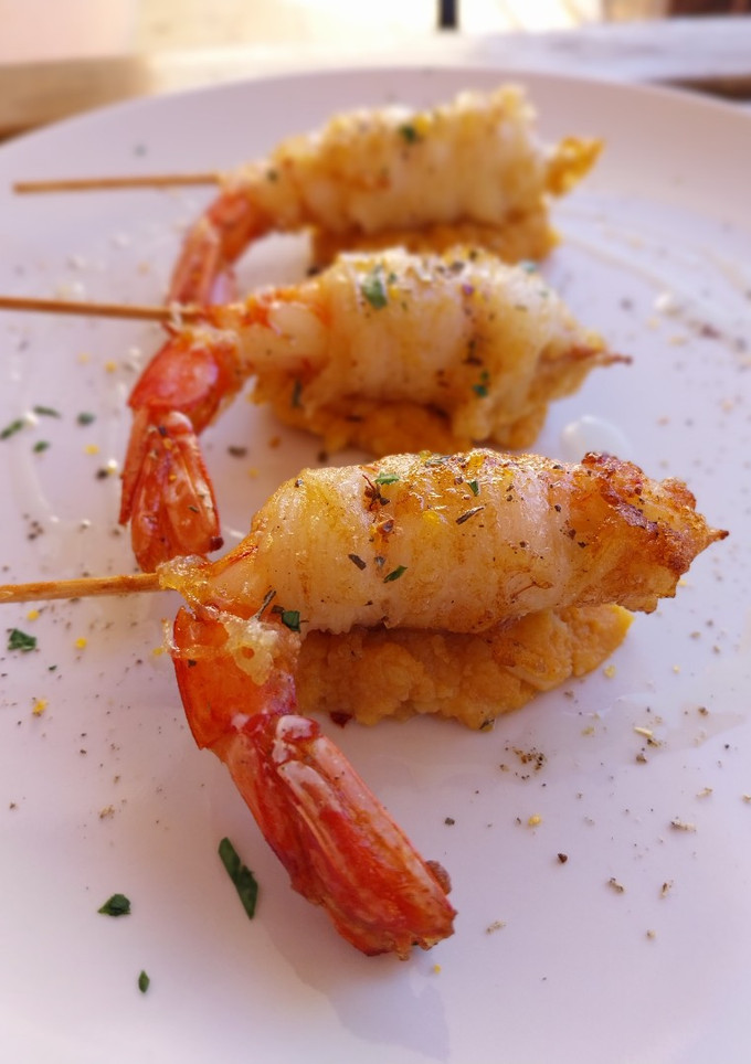 Una foto de Brocheta de gamba rebozada en fideo de arroz y quenelle de patatas revolconas