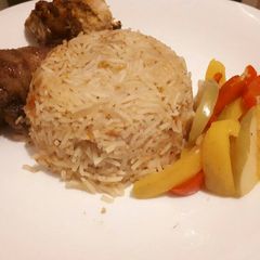 A picture of Jollof rice served with baked chicken.