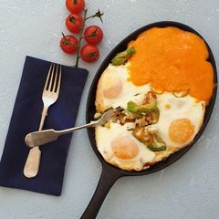 A picture of Baked eggs with tomatoes and avocado.