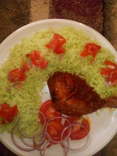 A picture of Colourd Rice with chicken stew and tomato's.