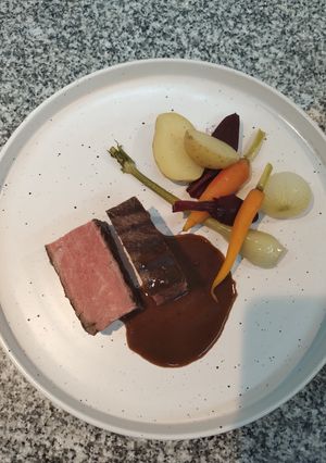 Una foto de Bife de chorizo con papines, puerro, zanahoria y remolachas baby