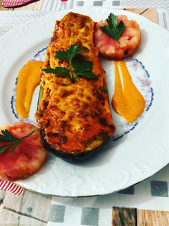 Una foto de Calabacines rellenos con gratinado de queso de oveja y salsa de pimientos del piquillo