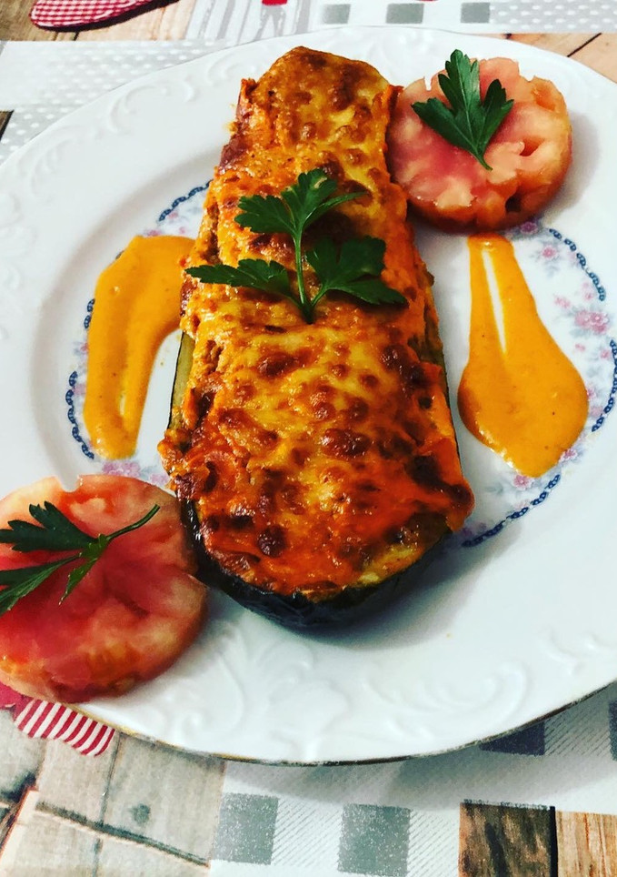 Una foto de Calabacines rellenos con gratinado de queso de oveja y salsa de pimientos del piquillo