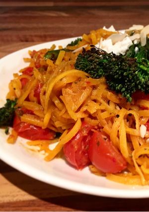 A picture of Butternut squash zoodles stir fry in spicy thai sauce, cherry tomatoes, broccolini, feta.