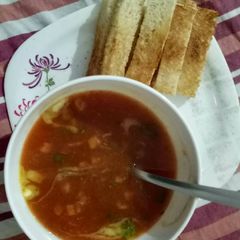 A picture of Tomato and carrot soup with bread sticks.