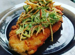 Una foto de Milanesa de pollo con topping de ensalada de Cangrejo