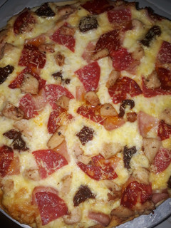 Una foto de Pizza de chorizo vela, salami, jamón y tomates secos