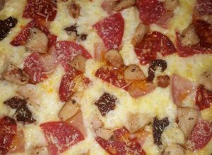 Una foto de Pizza de chorizo vela, salami, jamón y tomates secos