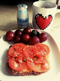 Una foto de Desayuno: tostada con tomate y aceite oliva, té y yogurt, uvas😍