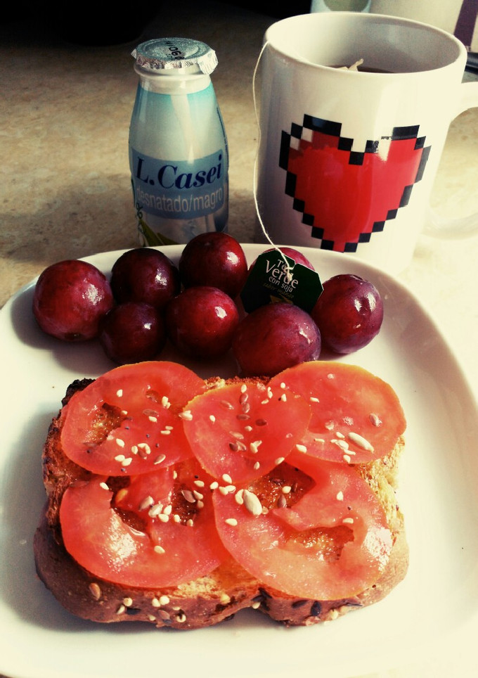 Una foto de Desayuno: tostada con tomate y aceite oliva, té y yogurt, uvas😍