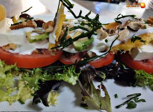 Una foto de Ensalada de queso fresco con tomate raf, aguacates, mango, salsa de yogurt y frutos secos