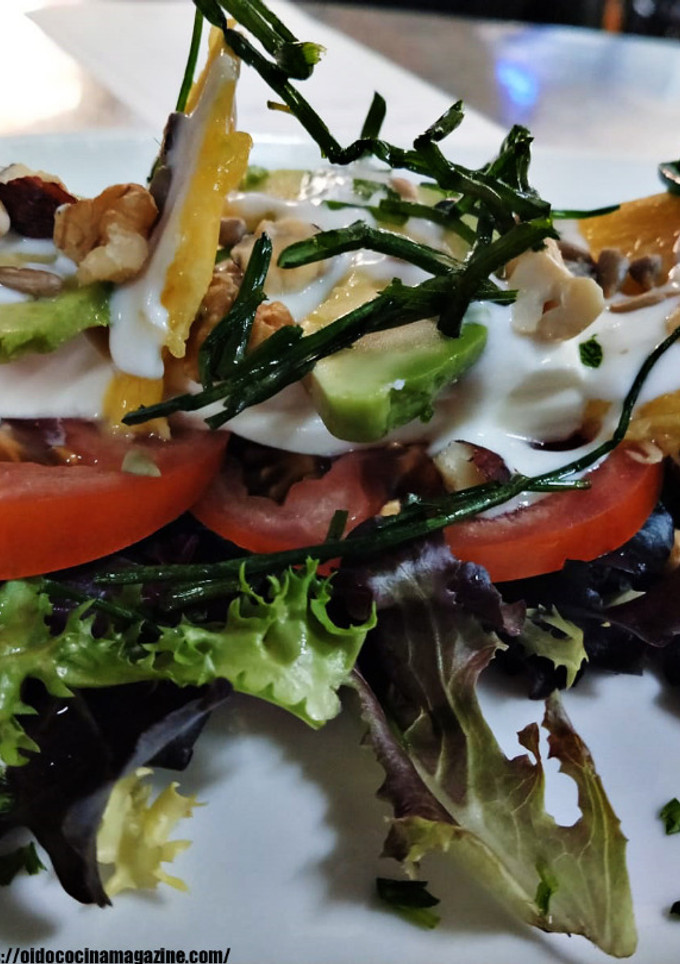Una foto de Ensalada de queso fresco con tomate raf, aguacates, mango, salsa de yogurt y frutos secos