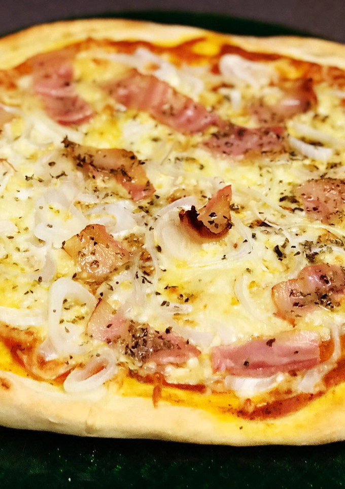 Una foto de Pizza de bacon y mucha cebolla con salsa casera de tomate, albahaca y orégano y masa artesanal