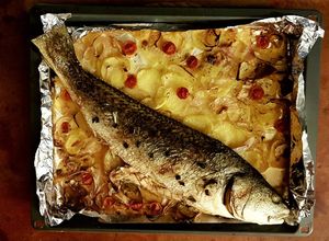 Una foto de Corvina al horno con lecho de patatas y cebolla
