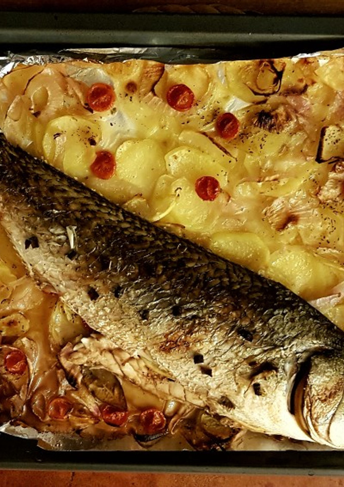 Una foto de Corvina al horno con lecho de patatas y cebolla
