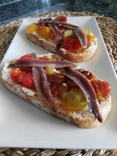 Una foto de Tostadas de queso, cherry caramelizados y anchoa