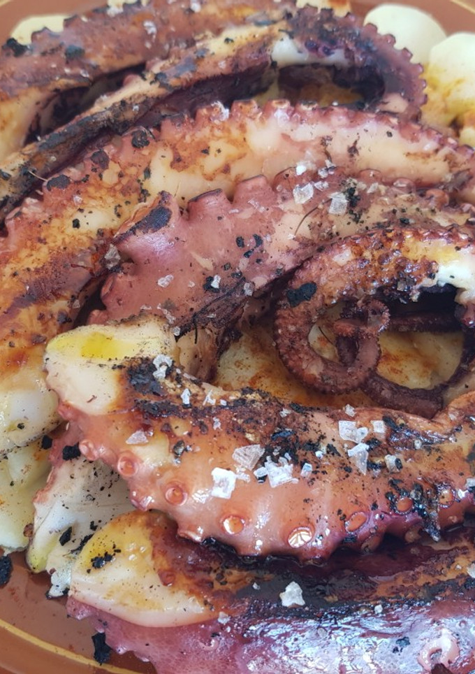 Una foto de Patas de pulpo a la brasa con lecho de patatas y pimentón