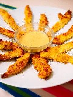 Una foto de Delicias de pollo crujiente con rebozado de panko y parmesano, acompañadas de salsa miel y mostaza