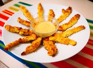 Foto principal de Delicias de pollo crujiente con rebozado de panko y parmesano, acompañadas de salsa miel y mostaza