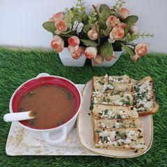 A picture of Tomato soup with cheese garlic bread.