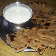 A picture of Onion paratha with curd.