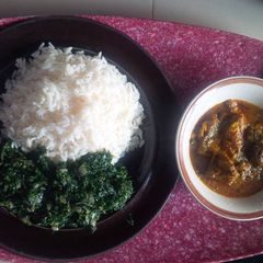 A picture of Rice with ofe akwu and vegetable.