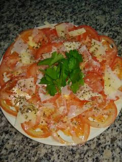 Una foto de Carpaccio de tomate con parmesano y albahaca