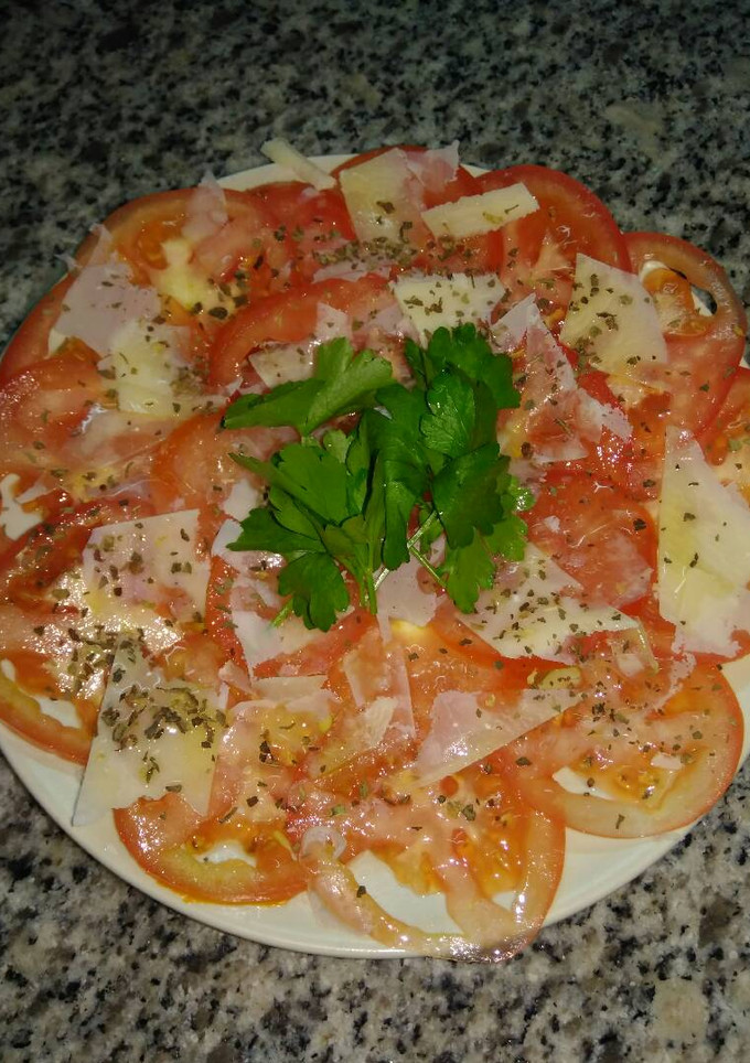 Una foto de Carpaccio de tomate con parmesano y albahaca