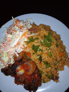 A picture of Jollof Rice/peppered Goat meat /Cole slaw.