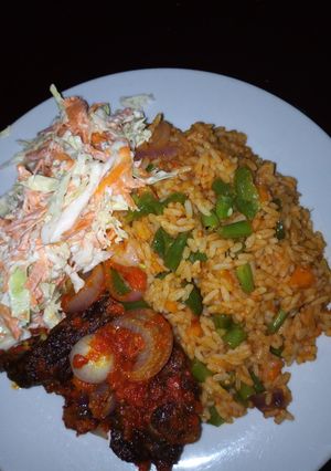 A picture of Jollof Rice/peppered Goat meat /Cole slaw.