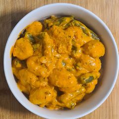 A picture of Gnocci with a creamy red pesto sauce & green beans.