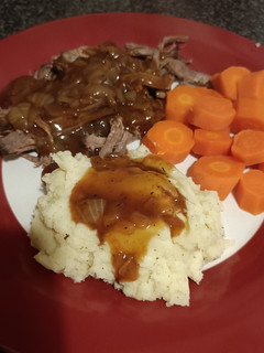 A picture of Slow cooked beef brisket, mash carrots and onion gravy.