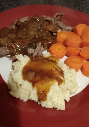 A picture of Slow cooked beef brisket, mash carrots and onion gravy.