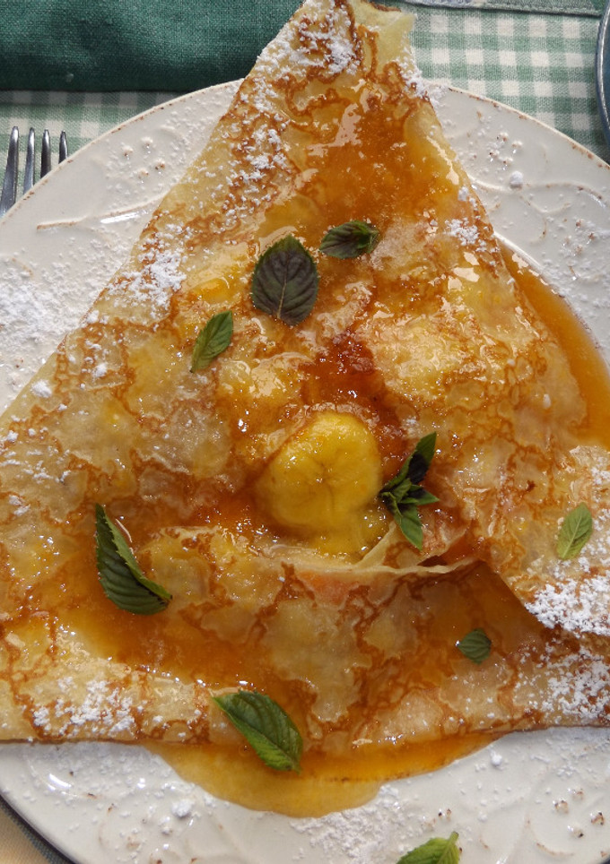 Una foto de Crepê rellena de plátano y albaricoques con almíbar de limón