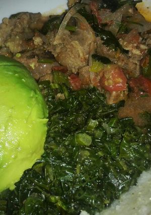 A picture of Beef stew served with ugali and saute kale.