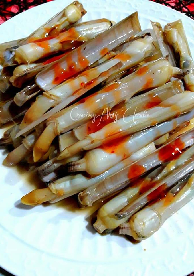 Una foto de Navajas a la plancha con escamas de sal al limón y salsa thai