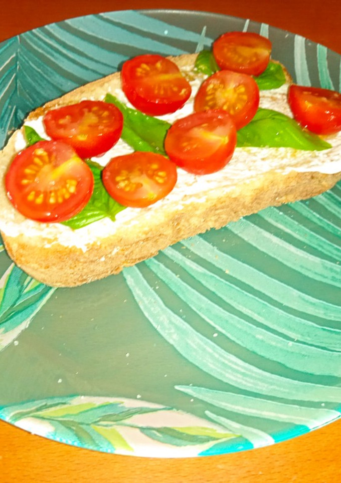 Una foto de Tostada de queso crema, cherrys y albahaca