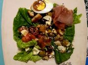 Una foto de ensalada con jamón serrano y fruta