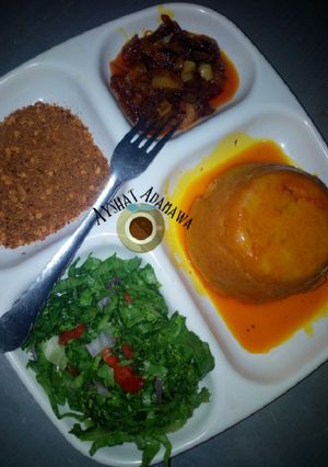 A picture of Moi moi with palm oil sauce and lettuce.