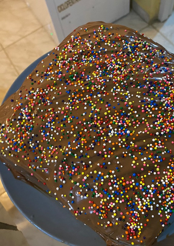 Una foto de Pastel de chocolate relleno de dulce de leche y ganache de chocolate con sprinkles