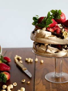 Una foto de Pavlova con ganache de chocolate negro, frutos secos y fresas