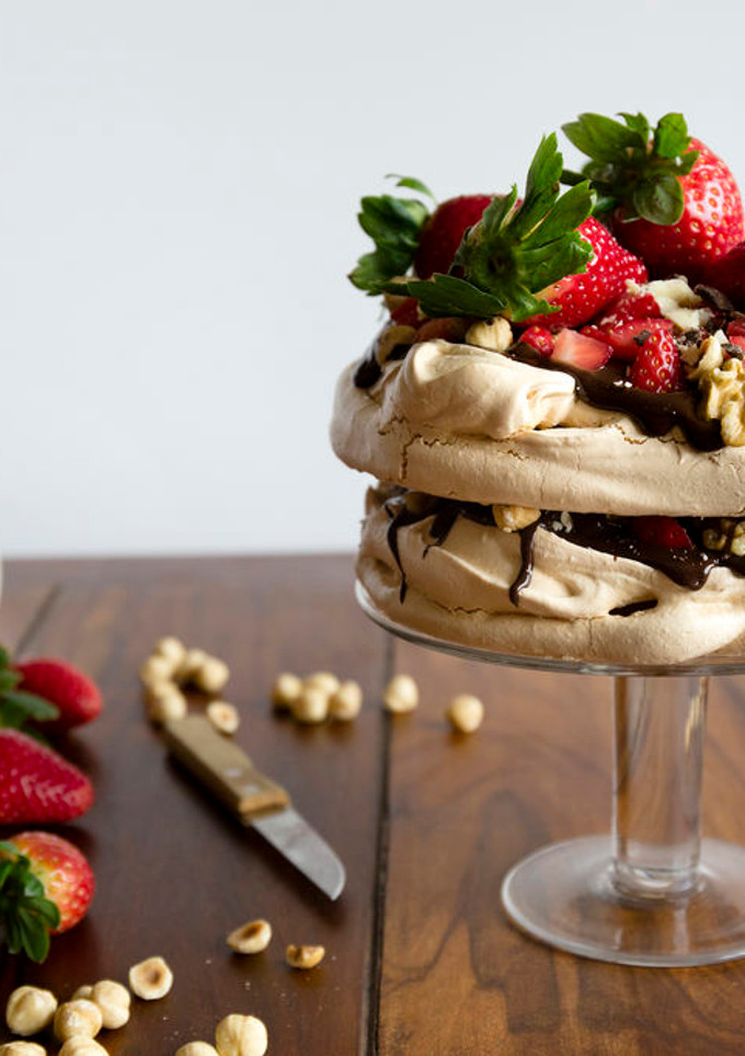 Una foto de Pavlova con ganache de chocolate negro, frutos secos y fresas
