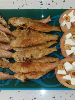 Una foto de Salmonetes fritos y tomates con queso y aceitunas