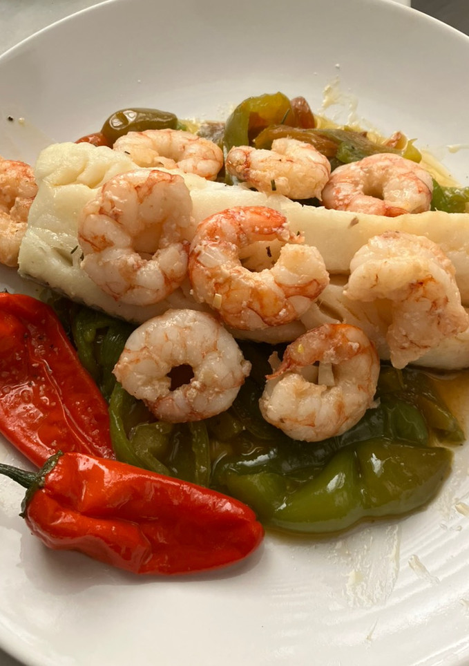 Una foto de Bacalao skrei con gambones al ajillo, sobre cama de pimientos